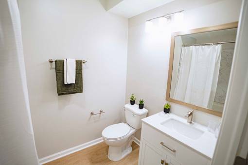 A white bathroom with a toilet, sink, and mirror.