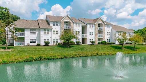 A large white apartment building with a fountain in front of it.