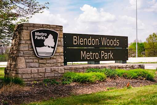 A sign for Blendon Woods Metro Park is displayed in front of a stone pillar.