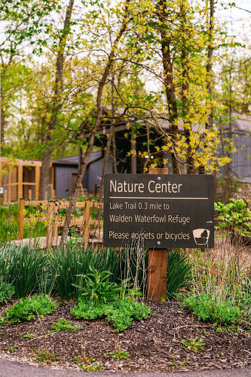A nature center sign is in front of a building and trees.