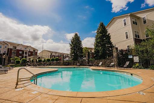 A swimming pool surrounded by a stone wall and trees.