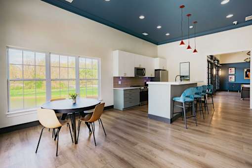 A kitchen with a table and chairs in front of a window.