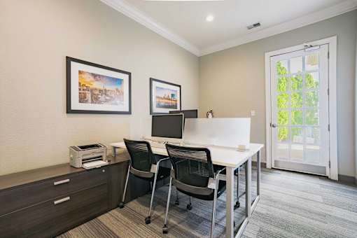 A room with a desk, chairs, and pictures on the wall.