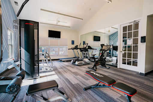 A gym with a variety of equipment including treadmills, weights, and exercise machines.