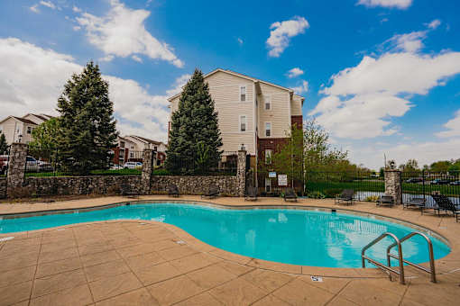 A swimming pool surrounded by a stone wall and trees.