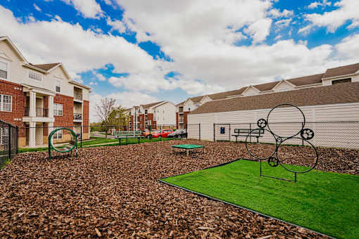 A playground with a green surface and a swing set.