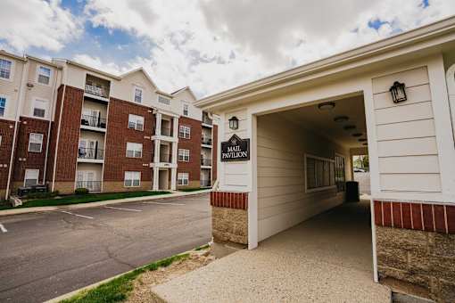 The entrance to a Pwylon apartment complex with a parking lot in front.