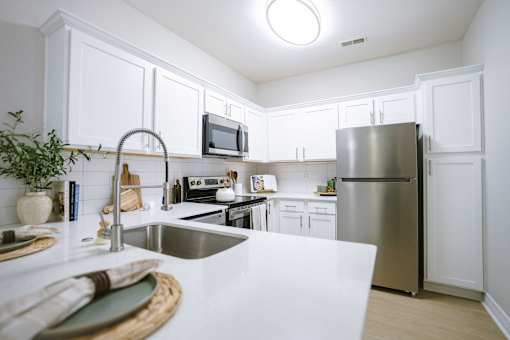 A kitchen with white cabinets and a stainless steel refrigerator.