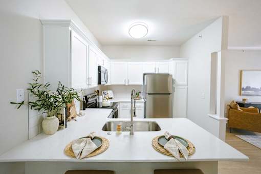 A kitchen with a white counter top and a stainless steel refrigerator.