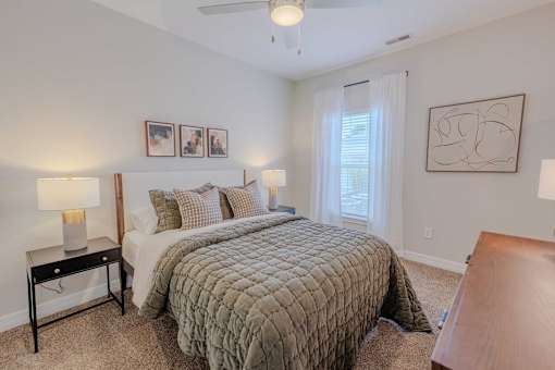 A bedroom with a bed, nightstand, and pictures on the wall.