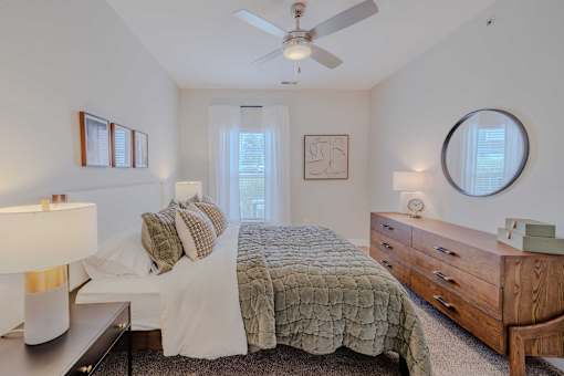 A bedroom with a bed, dresser, and window.