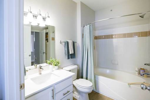 A white bathroom with a white toilet, sink, and bathtub.