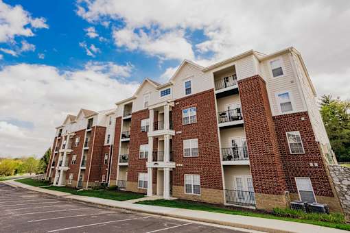 A large apartment building with a parking lot in front.