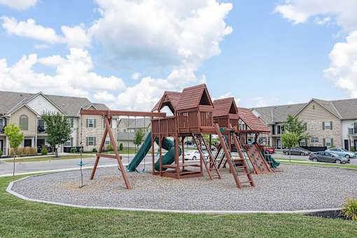 A playground with a green slide and a brown wooden structure.