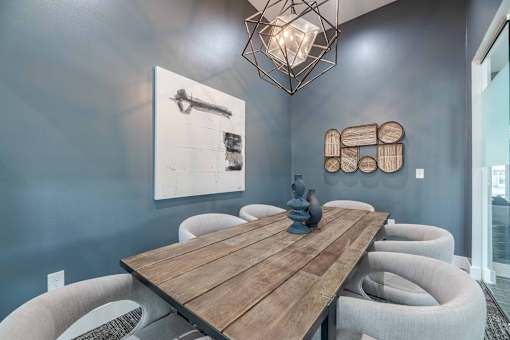A wooden table is surrounded by grey chairs in a room.
