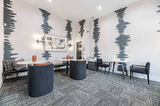 A room with a grey carpet and a grey and black abstract wallpaper.