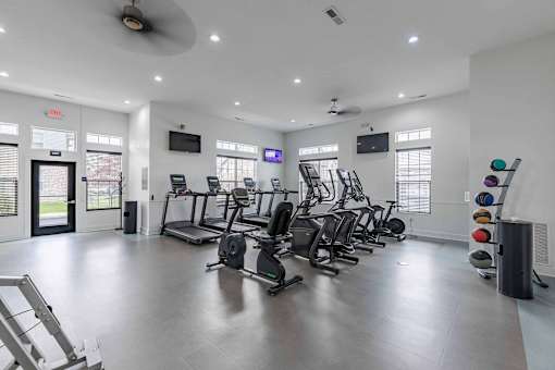 A gym with a variety of exercise equipment including treadmills, stationary bikes, and weight machines.