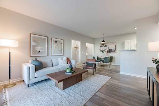A living room with a white couch, a coffee table, and a dining table with chairs.