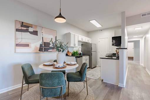 A dining area with a table set for four and a kitchen in the background.