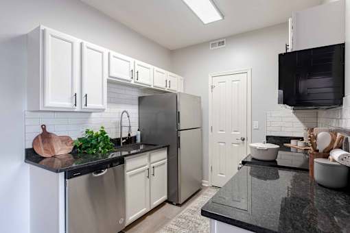 A kitchen with white cabinets and a black countertop.