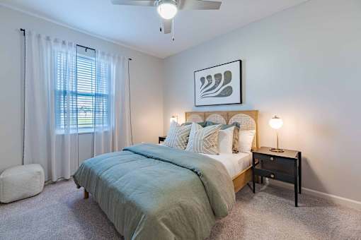 A bedroom with a bed, nightstand, and a ceiling fan.
