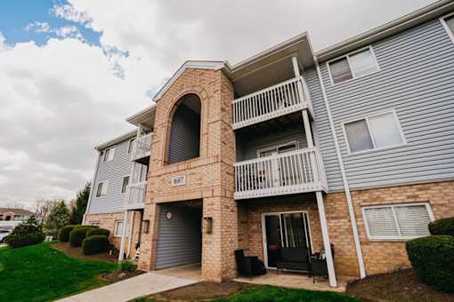 A two-story apartment building with a balcony and a garage door.