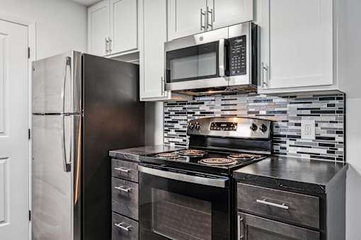 A kitchen with a black refrigerator, black stove, and black oven.