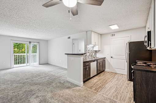 A spacious kitchen with a bar area and a ceiling fan.
