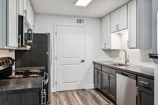 A kitchen with black appliances and white cabinets.