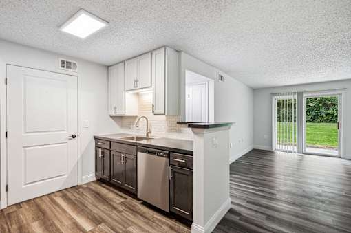 A kitchen with white cabinets and a black dishwasher.