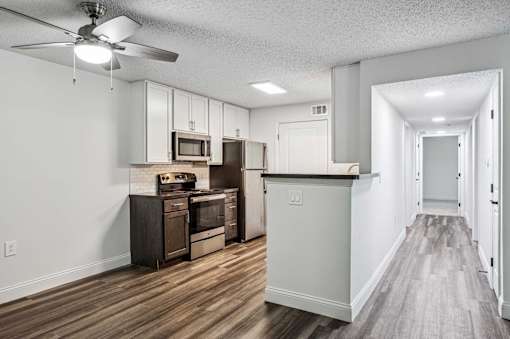 A kitchen with wood floors and white walls.