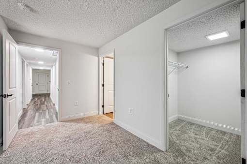 A spacious room with a carpeted floor and white walls.