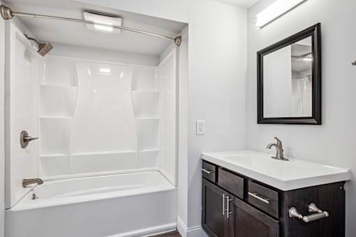 A white bathroom with a black framed mirror.