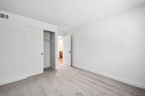 A room with a carpeted floor and two doors.