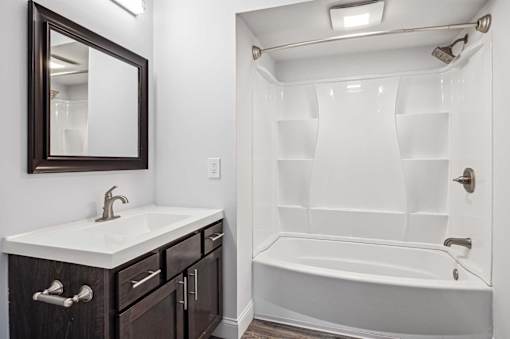 A white sink with a silver faucet and a brown mirror above it.