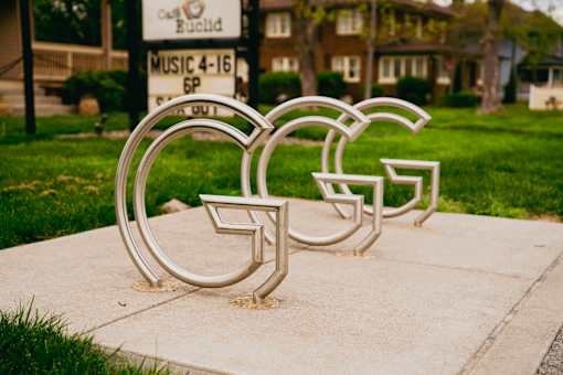 A metal sculpture of the letters G, F, and C is displayed on a sidewalk.