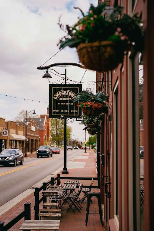 A sign for a brewery hangs over a sidewalk.