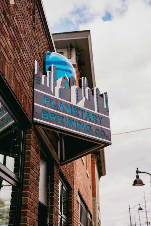 A sign for a brewery hangs on a building.