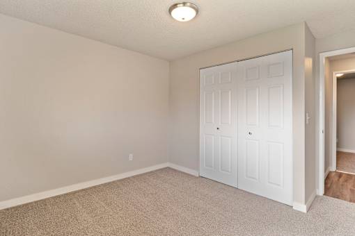 A white door is in a room with carpeted floor.