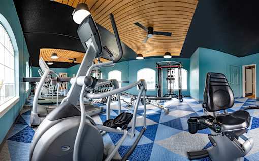 A gym with a variety of exercise equipment including treadmills, stationary bikes, and weight machines.