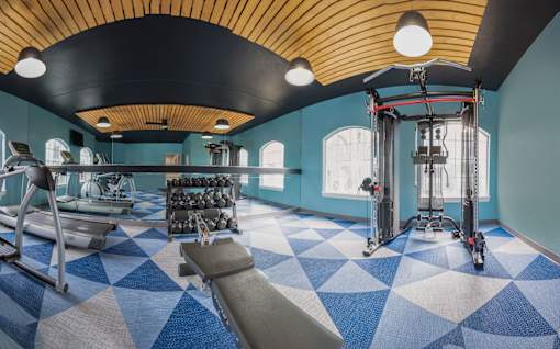 A gym with a variety of equipment including a treadmill, weights, and a leg press machine.