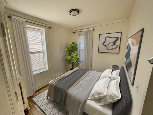 A bedroom with a bed, a plant, and two pictures on the wall.