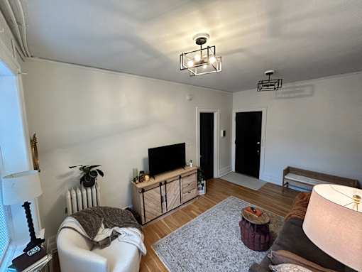 A living room with a white couch, a television, and a wooden cabinet.