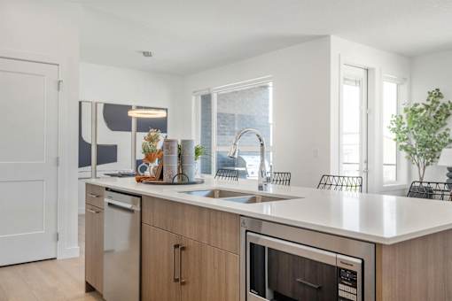 A modern kitchen with a white countertop and stainless steel appliances.