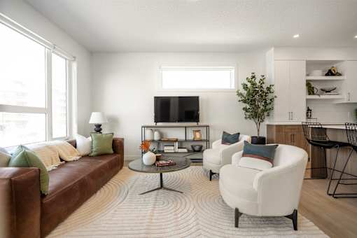 A living room with a brown couch, a white chair, and a coffee table.