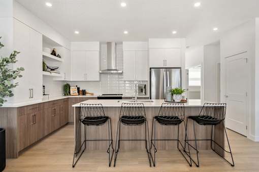 A modern kitchen with a bar area and three black chairs.