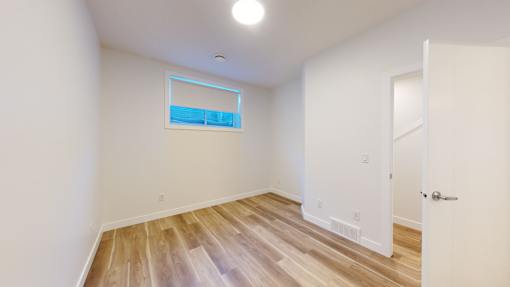 A room with a white door and a window with a blue sky reflection.