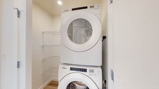 A white dryer is stacked on top of a white washing machine.