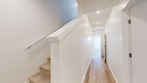 A long hallway with a staircase on the left and a door on the right.