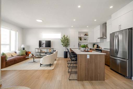 A modern kitchen with a refrigerator, stove, and island with a countertop and chairs.